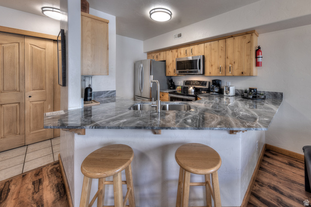 3461 Westwater Road, Unit 6 Moab, UT 84532 - Photo 11 of 33 Kitchen with a kitchen bar, dark wood-style flooring, a peninsula, stainless steel appliances, and dark stone counters