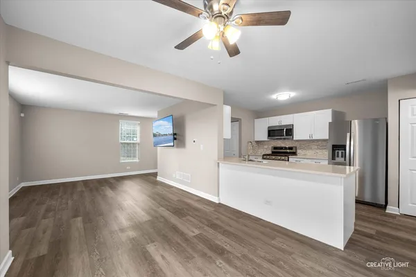 a view of kitchen with stainless steel appliances refrigerator stove microwave and cabinets