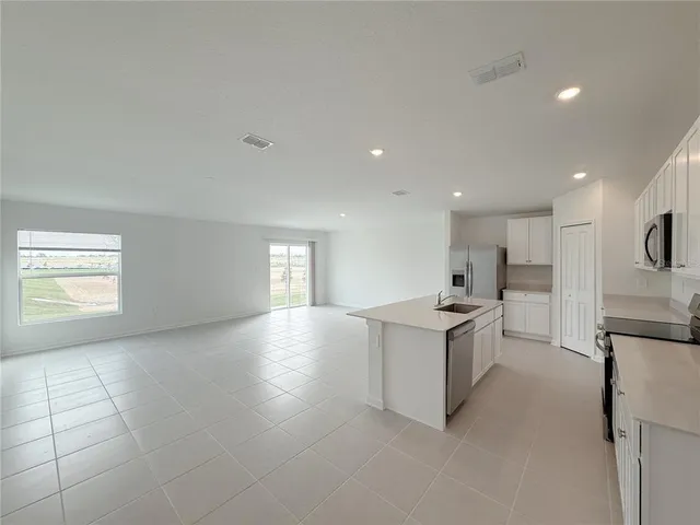 a living room with stainless steel appliances kitchen island granite countertop a stove and a sink