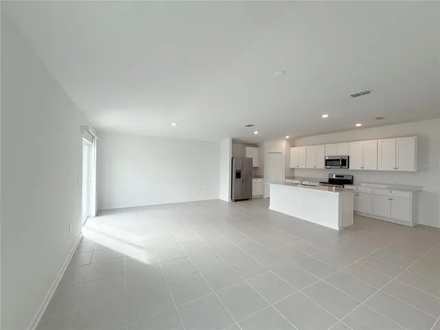 a view of kitchen with kitchen island stainless steel appliances refrigerator sink and cabinets