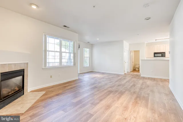 a view of empty room with wooden floor and fireplace