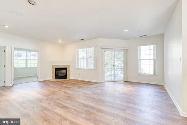 an empty room with windows fireplace and wooden floor