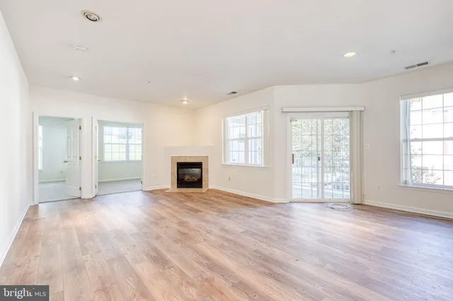 an empty room with windows and fireplace