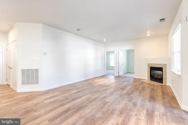 a view of empty room with wooden floor and fireplace