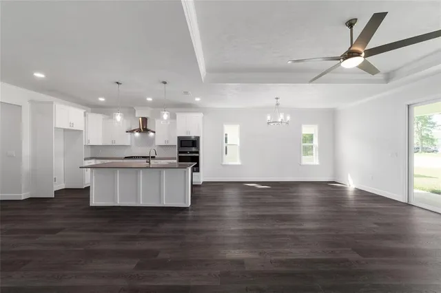 a view of kitchen with kitchen island white cabinets wooden floor and a sink