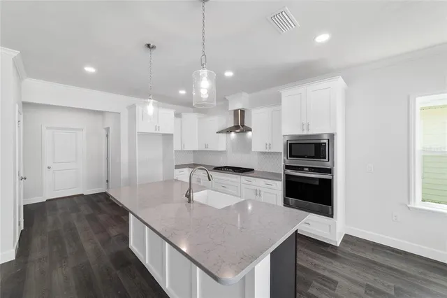 a kitchen with kitchen island white cabinets and stainless steel appliances