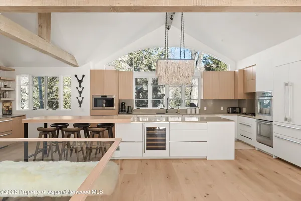 a large white kitchen with kitchen island a large counter top a sink stainless steel appliances and cabinets