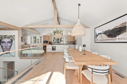 a dining room with wooden floor a chandelier a wooden table and chairs