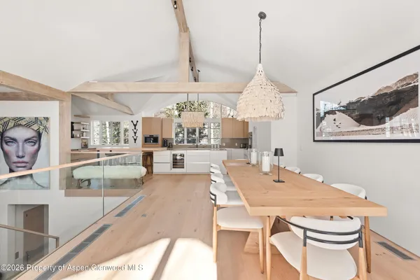 a dining room with wooden floor a chandelier a wooden table and chairs