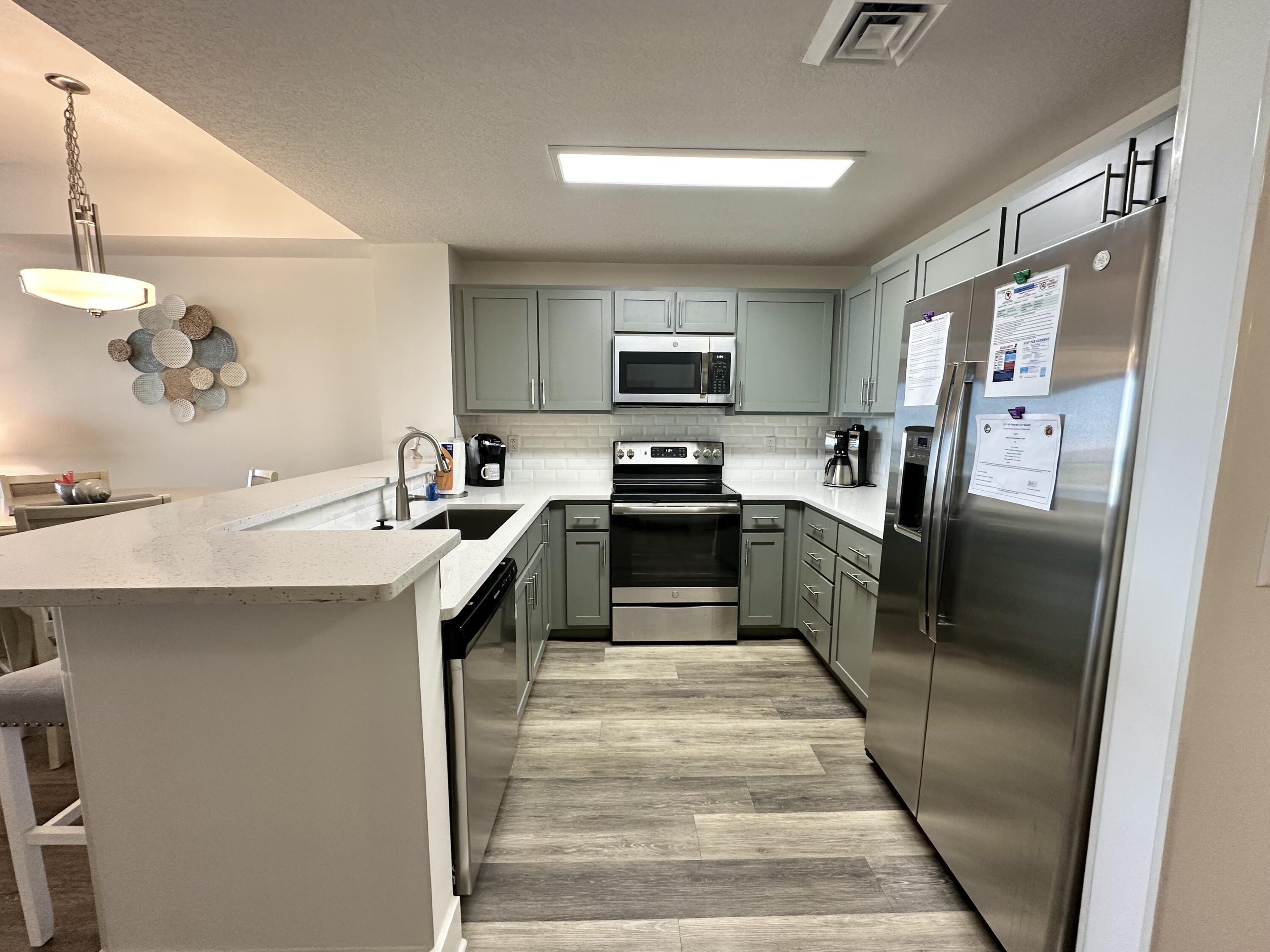 15928 Front Beach Road, Unit 3702 Panama City Beach, FL 32413 - Photo 14 of 85 a kitchen with stainless steel appliances a refrigerator a sink a stove top oven a counter space and cabinets