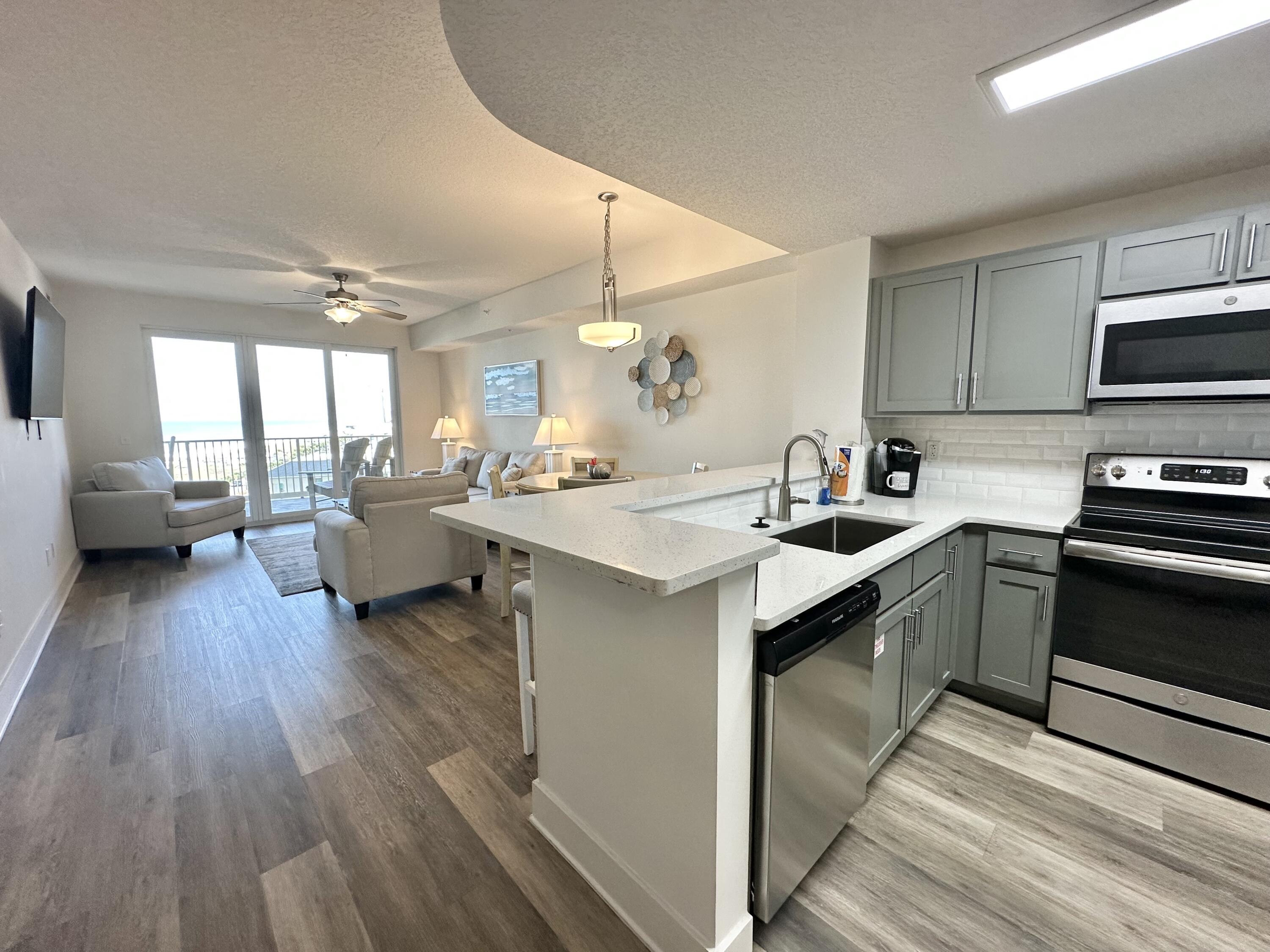 15928 Front Beach Road, Unit 3702 Panama City Beach, FL 32413 - Photo 15 of 85 a kitchen with a sink dishwasher stove and white cabinets with wooden floor