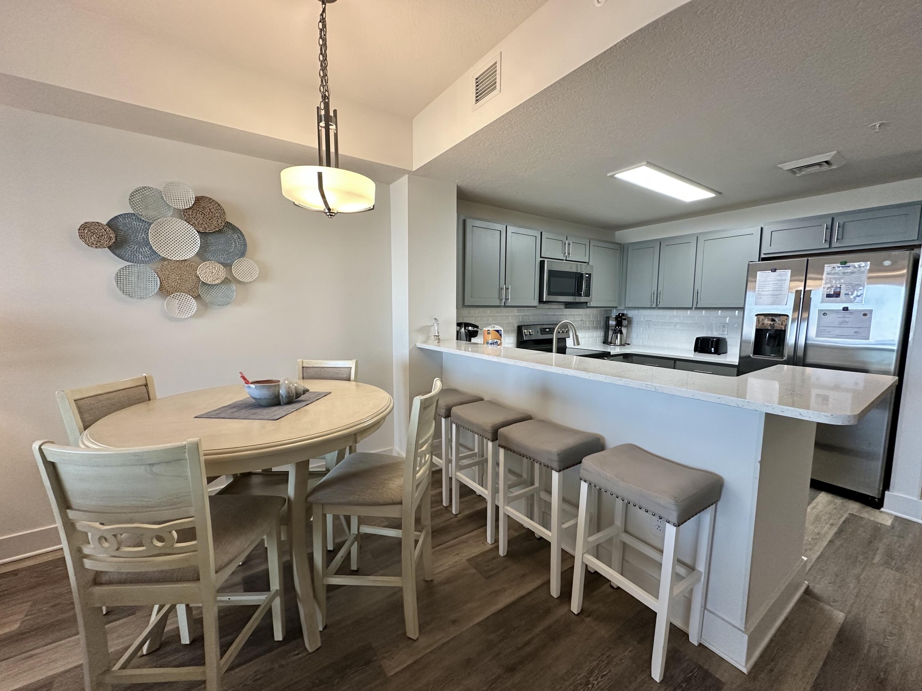 15928 Front Beach Road, Unit 3702 Panama City Beach, FL 32413 - Photo 34 of 85 a kitchen with stainless steel appliances granite countertop a sink a stove a dining table and chairs