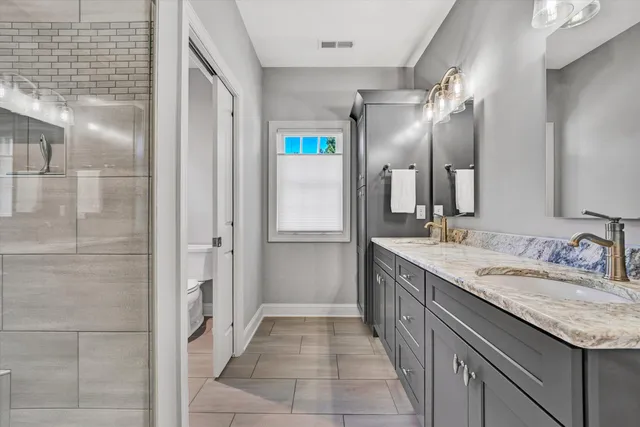 a bathroom with a granite countertop toilet sink and mirror