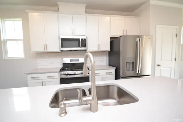 a kitchen with granite countertop a sink stove and refrigerator