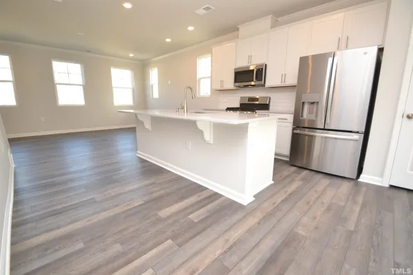 a kitchen with stainless steel appliances a refrigerator a stove a microwave and white cabinets