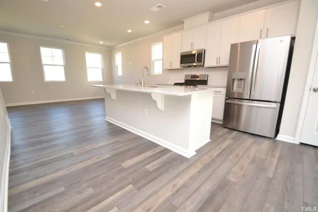 a kitchen with stainless steel appliances a refrigerator a stove a microwave and white cabinets