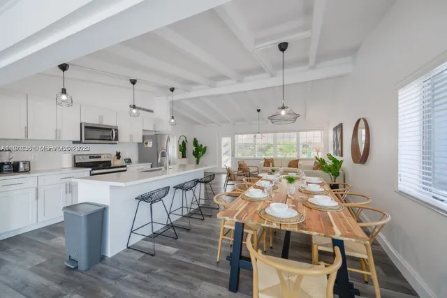 a view of kitchen with microwave a stove and white cabinets with wooden floor