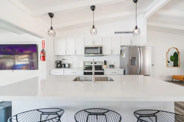 a kitchen with stainless steel appliances a stove a refrigerator and a dining table with white countertops