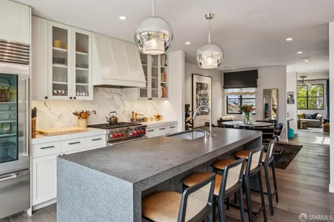 a kitchen with stainless steel appliances granite countertop a stove top oven a sink a dining table and chairs with wooden floor