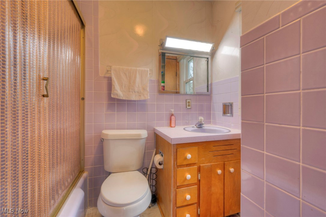 679 Garnette Road Akron, OH 44313 - Photo 22 of 47 Bathroom with toilet, tile walls, vanity, and shower / bath combination with curtain