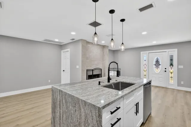 a kitchen with stainless steel appliances granite countertop a stove a refrigerator and a sink with wooden floors