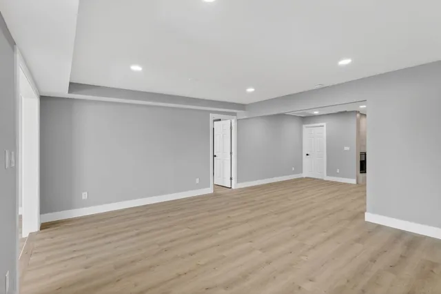 a view of an empty room with wooden floor and a fireplace