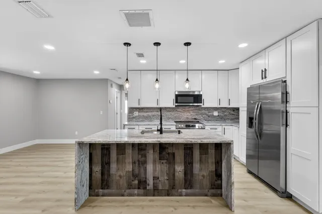a kitchen with kitchen island a dining table chairs stainless steel appliances and cabinets