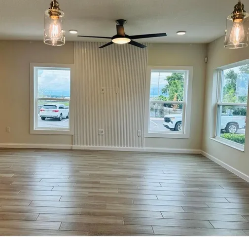 a view of an empty room with a window and wooden floor
