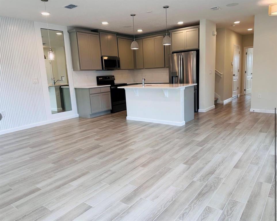 2895 Narcoossee Cmns Way St. Cloud, FL 34771 - Photo 8 of 10 a kitchen with stainless steel appliances kitchen island granite countertop a refrigerator and a stove top oven