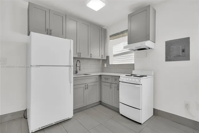 a view of a kitchen with refrigerator and white cabinets