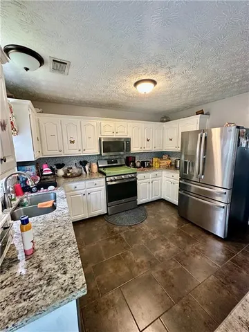 a kitchen with stainless steel appliances granite countertop a sink dishwasher stove top oven and refrigerator