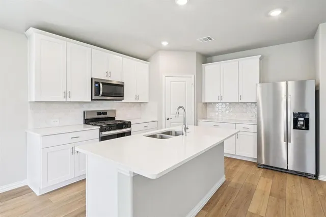 a kitchen with a sink a stove a refrigerator a white counter top space and cabinets
