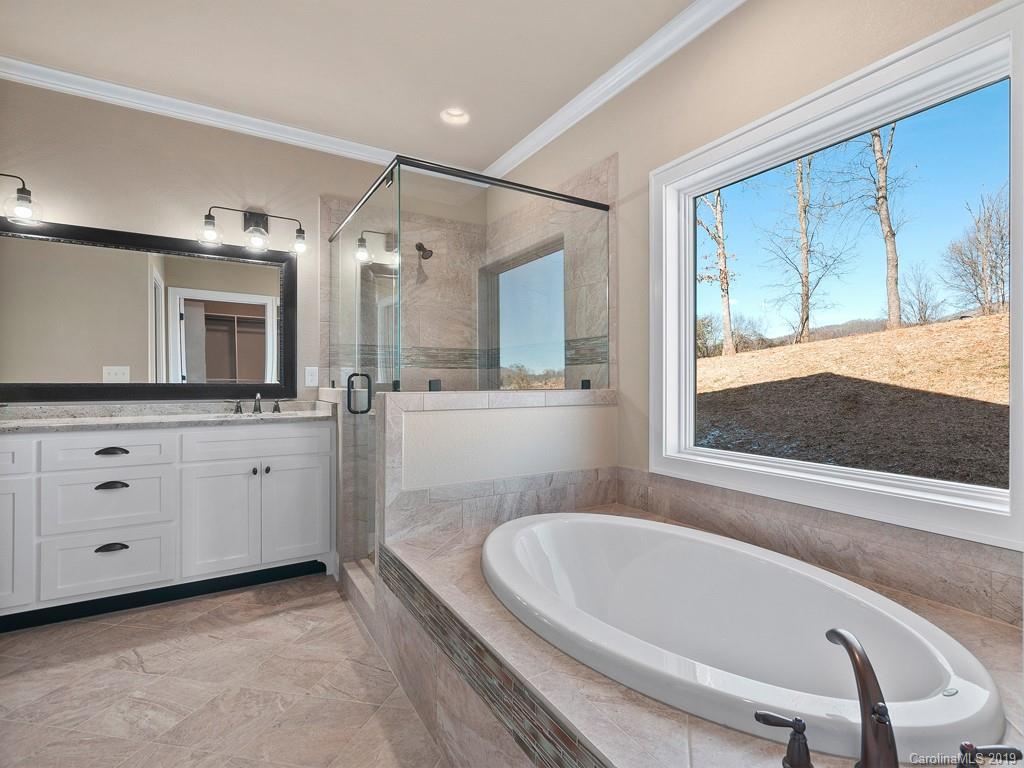 28 Jasper Ridge Clyde, NC 28721 - Photo 19 of 24 a bathroom with a bathtub a mirror a sinks and vanity