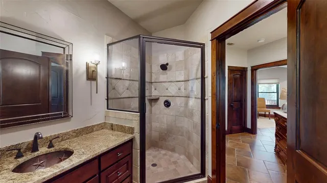 a bathroom with a granite countertop shower sink and mirror