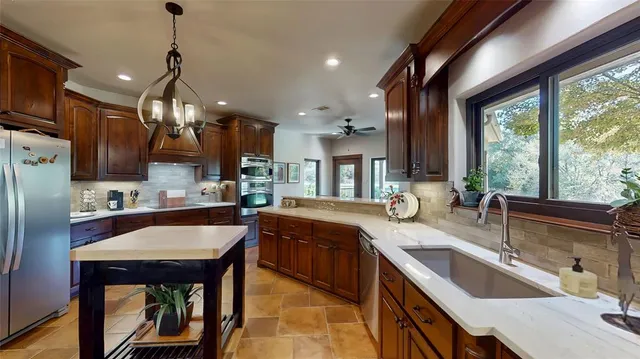 a kitchen with stainless steel appliances granite countertop a sink a stove and a refrigerator