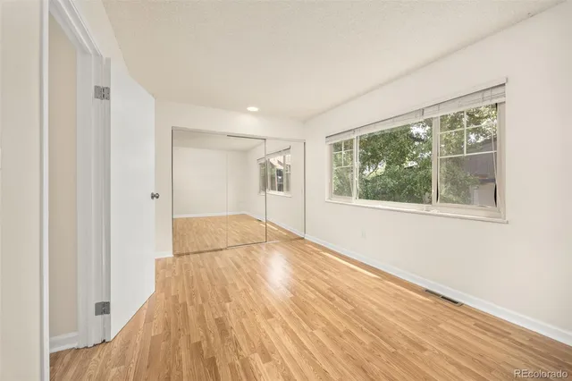 a view of empty room with wooden floor and fan