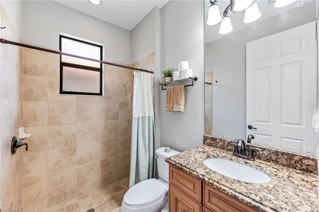 a bathroom with a granite countertop sink toilet and shower