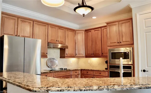 a kitchen with stainless steel appliances granite countertop a refrigerator a stove and a sink with wooden floor