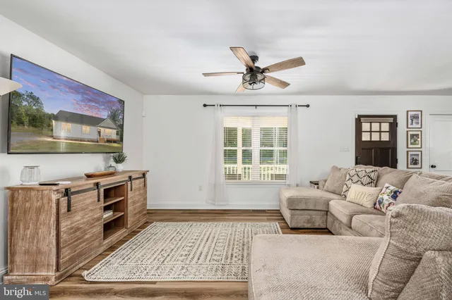 a kitchen with stainless steel appliances granite countertop a refrigerator a stove a sink a dining table and chairs with wooden floor