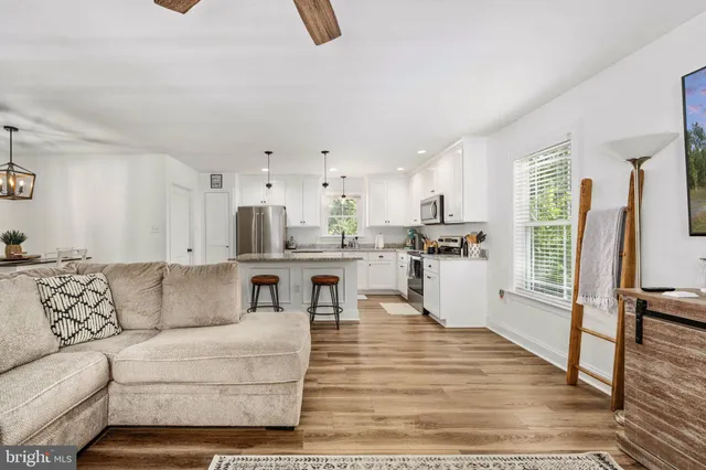 a kitchen with stainless steel appliances granite countertop a stove a sink dishwasher a refrigerator and white cabinets with wooden floor