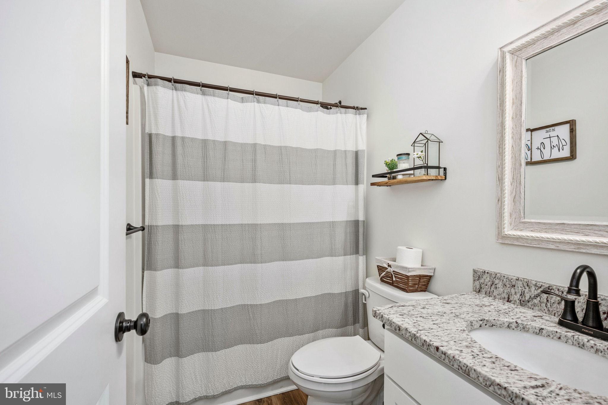 5712 Buckner Road Bumpass, VA 23024 - Photo 31 of 59 a bathroom with a granite countertop bathtub sink vanity mirror and toilet