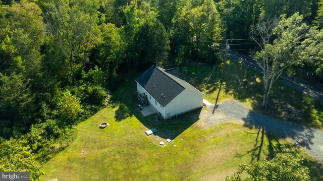 an aerial view of a house with swimming pool and trees all around