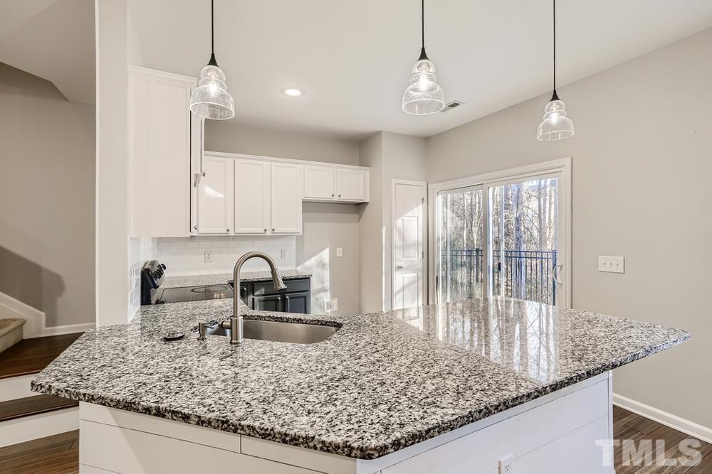 7012 Racine Way Raleigh, NC 27690 - Photo 13 of 28 a kitchen with kitchen island granite countertop a sink a counter top space and cabinets