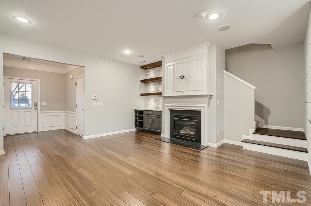 7012 Racine Way Raleigh, NC 27690 - Photo 6 of 28 an empty room with wooden floor fireplace and windows