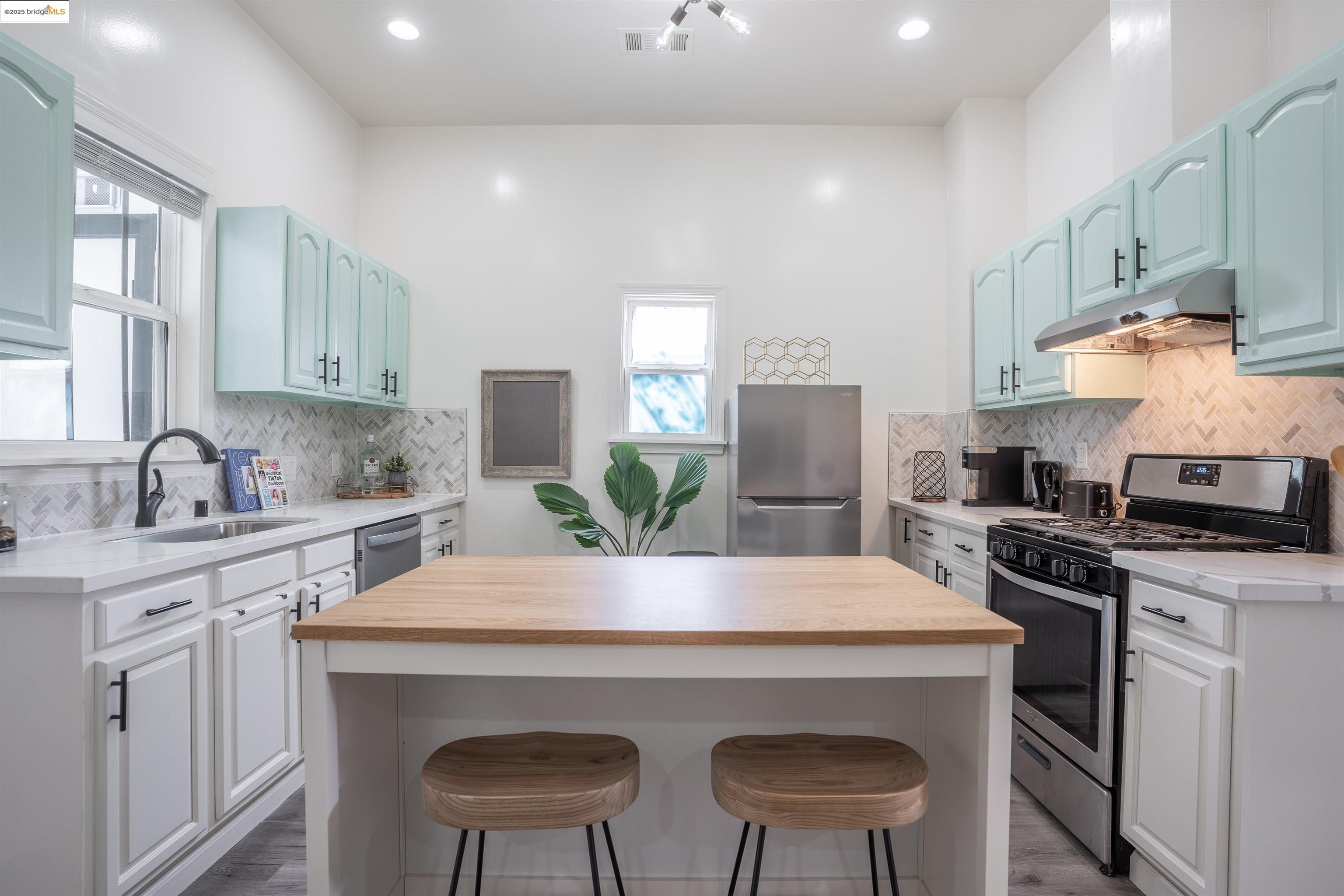 527 Chester Street Oakland, CA 94607 - Photo 55 of 59 Kitchen with wood counters, appliances with stainless steel finishes, a kitchen breakfast bar, under cabinet range hood, and plenty of natural light