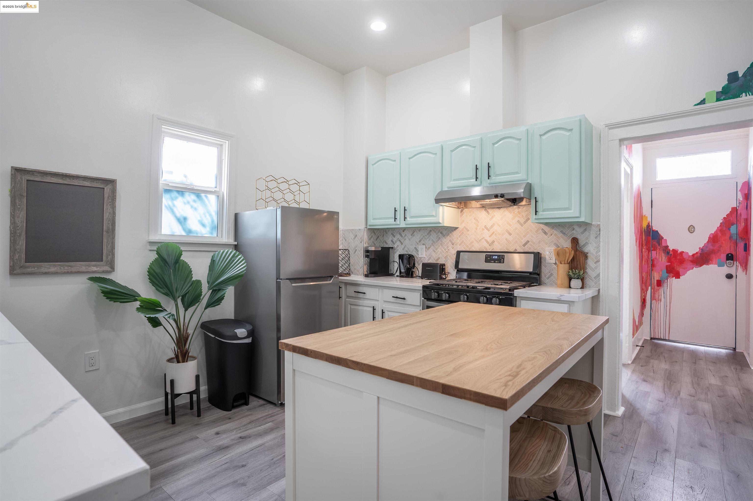 527 Chester Street Oakland, CA 94607 - Photo 56 of 59 Kitchen featuring wood counters, appliances with stainless steel finishes, a center island, a breakfast bar, and light wood finished floors