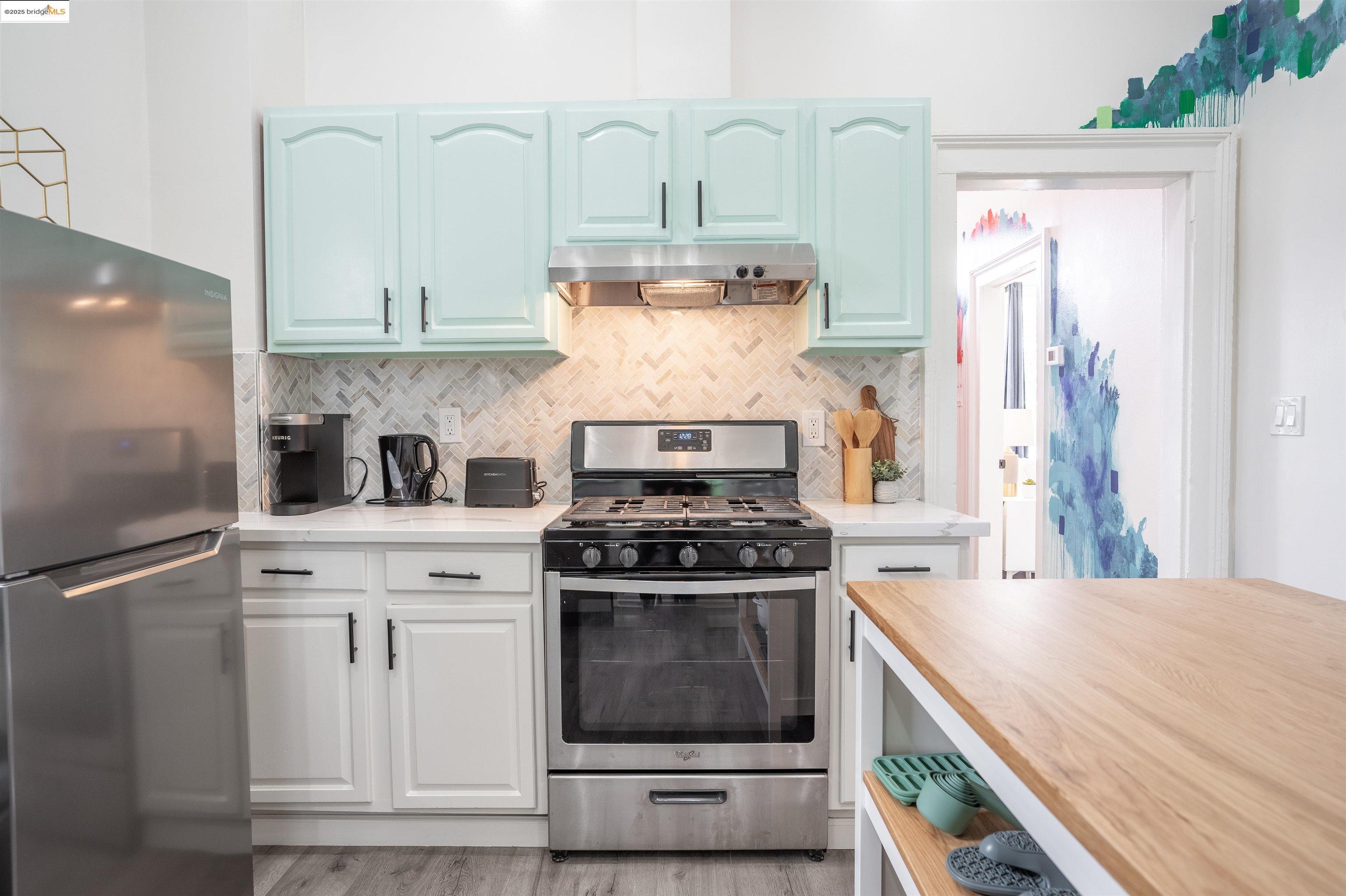 527 Chester Street Oakland, CA 94607 - Photo 58 of 59 Kitchen with appliances with stainless steel finishes, butcher block counters, decorative backsplash, under cabinet range hood, and light wood-style floors