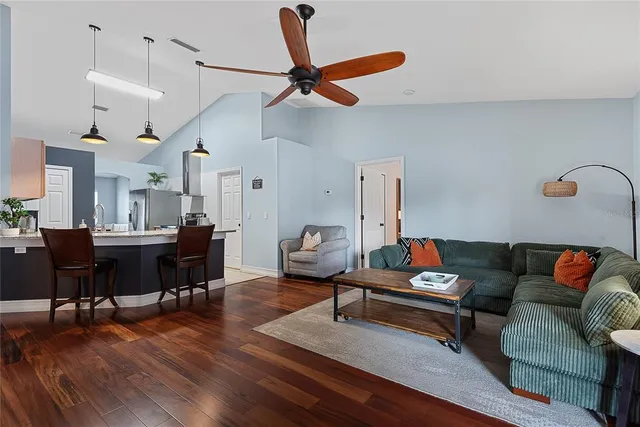 a living room with furniture kitchen view and a wooden floor