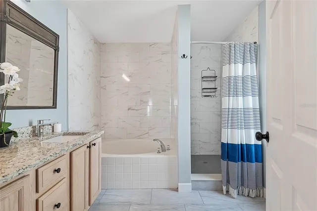 a bathroom with a granite countertop double vanity sink and mirror with bathtub