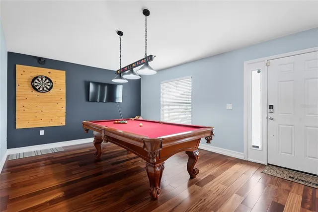 a room with pool table windows and wooden floor